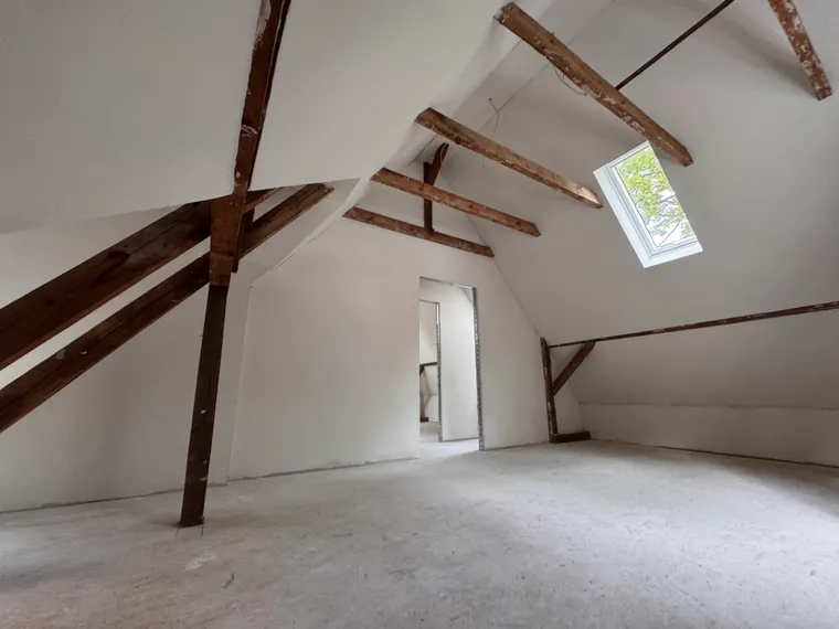 Dachausbau Referenz – helles offenes Dachgeschoss mit freiliegenden Holzbalken und Dachfenster in Berlin